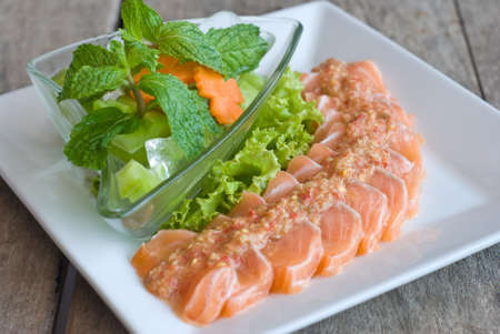 salmon sashimi topping with spicy sauce and fresh mix vegetableの写真素材
