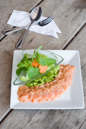 salmon sashimi topping with spicy sauce and fresh mix vegetableの写真素材