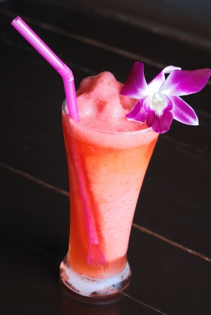 glass of watermelon juice decorated with orchid flower on black tableの写真素材