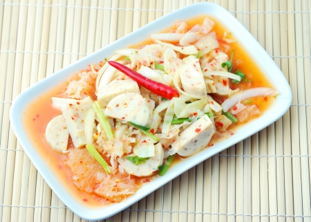 Thai cuisine - Vietnamese pork sausage spicy salad in white plate on bamboo matの写真素材