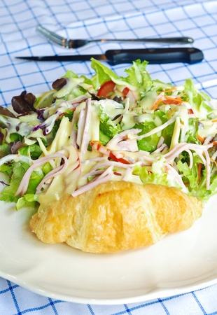 close up fresh vegetable salad with ham and cheese serves with croissantの写真素材