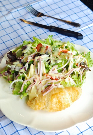 close up fresh vegetable salad with ham and cheese serves with croissantの写真素材