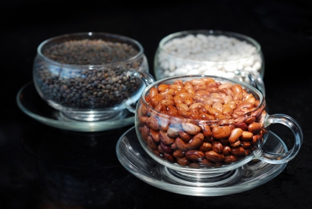 close up full of cranberry bean in glass cup with sesame and white bean cups on black の写真素材