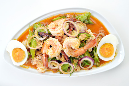 Selective focus of spicy seafood salad with egg on white background, Thai foodの写真素材