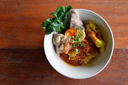 Selective focus of spicy egg noodle with pork rib and egg on wood background