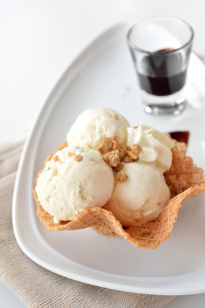 Selective focus of vanilla ice cream scoop with chocolate sauce on white backgroundの写真素材