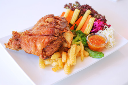 Selective focus of deep fry pork leg with spicy sauce and fresh vegetable on white backgroundの写真素材