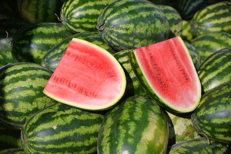 Cut in half of watermelon on watermelon heap in marketの写真素材