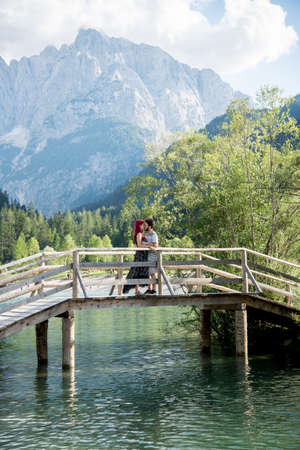 Couple kissing on the bridge with lake and mountains backgroundの写真素材