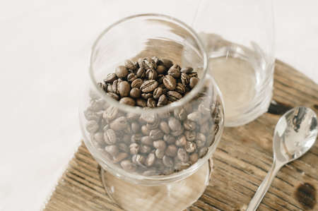 Coffee beans in a glass on a wooden coasterの写真素材