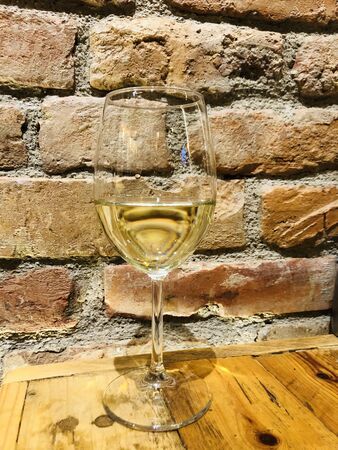 one glass of white wine with brick background.の写真素材