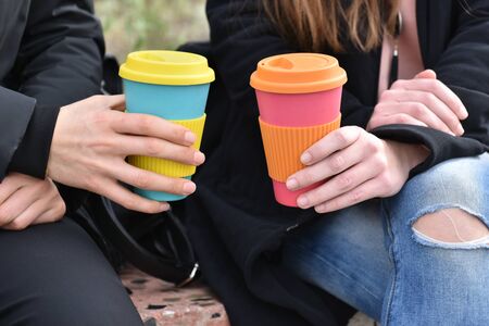 two girls sitting outdoors holding coffee cup .Sustainable lifestyleの写真素材