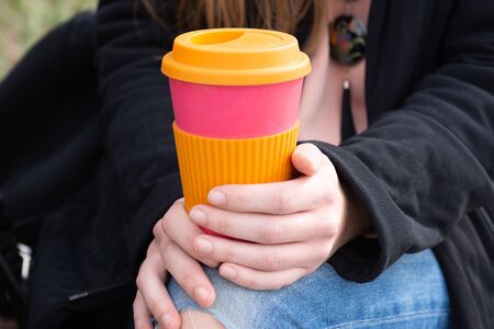 Female hand holding reusable coffee mug. Take your coffee to-go with reusable travel mug. Zero waste concept . Sustainable lifestyle concept. の写真素材