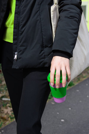 Female hands hold reusable coffee mug outdoors. Take your coffee to-go with reusable travel mug....
