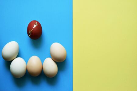 White Easter eggs on blue and yellow background with one red egg .の写真素材