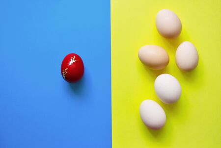 White Easter eggs on blue and yellow minimalist background with one egg on red color.Easter Element.Top View,Flat lay,copy space.の写真素材