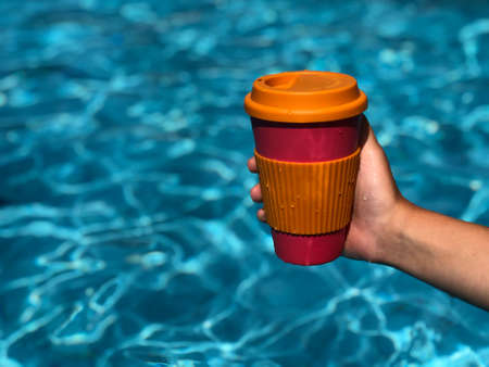 Woman enjoying coffee in a reusable bamboo mug at the swimming pool.Zero waste and Sustainable lifestyle concept.Take your coffee to-go with reusable travel mug.の写真素材