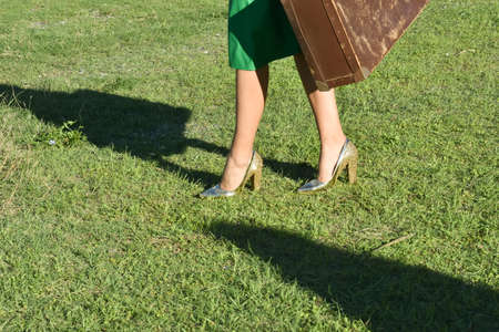 Woman in green dress walking and holding a suitcase in her hands,の写真素材