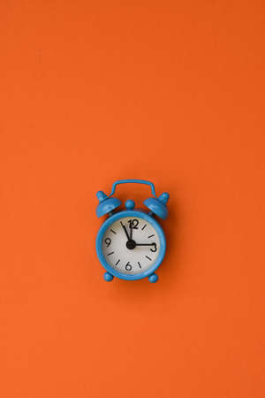 Blue alarm clock on orange background.Minimal flat lay concept.の写真素材