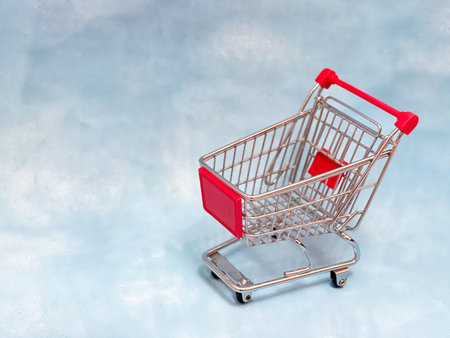 An empty mini supermarket cart on a blue background.