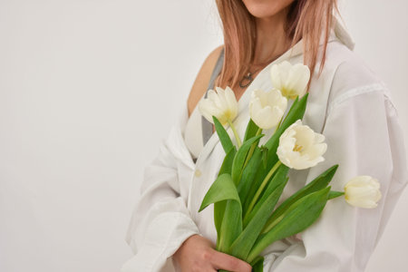 Bouquet of white tulips in a female hand on a white background.の写真素材