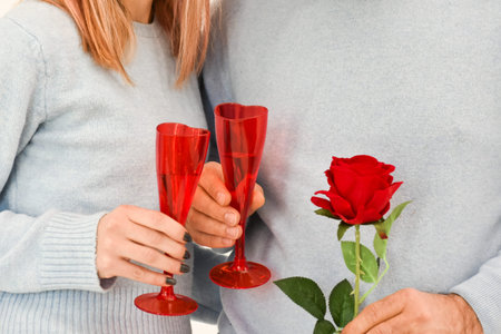 Lovely couple celebrating their love, holding two glasses and a rose.