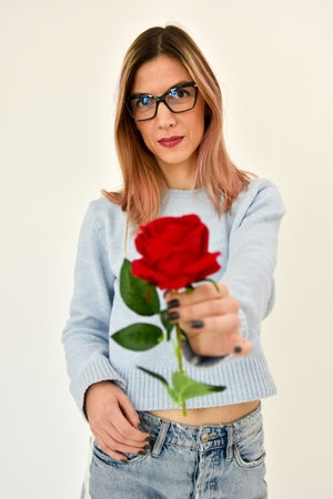 Valentines day background. Young female holds a red rose in her hand.の写真素材