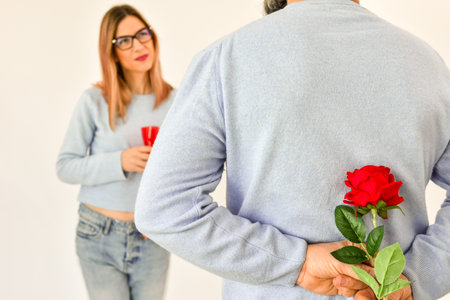 A man holding a red rose behind his back .の写真素材