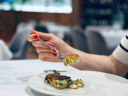 A girl with a fork in her hand enjoying food in a restaurant. Copy spaceの写真素材