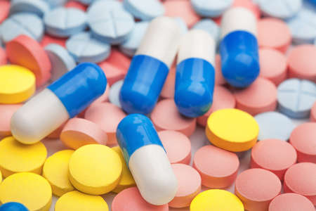 White and blue pills on background of colored medical pillsの写真素材