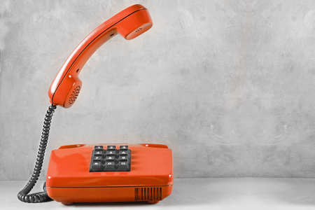 landline red phone on a gray wall background