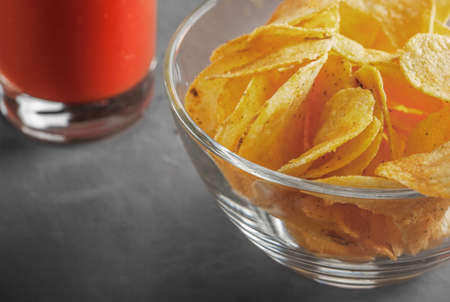 Potato chips in bowl with tomato juice in glassの写真素材
