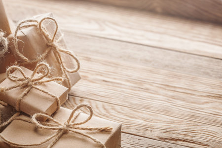 Gift box in kraft paper with bow on wooden background