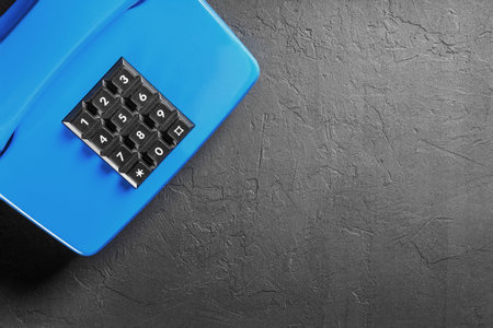 landline blue phone on a gray wall background