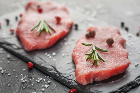 raw beef steak with rosemary and peppers on dark stoneの写真素材