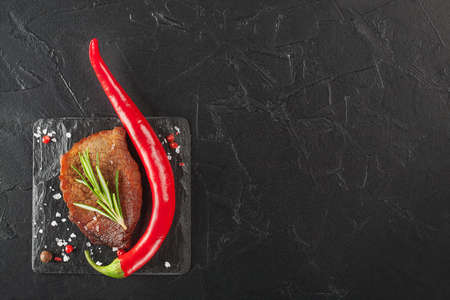 grilled steak with rosemary and chili pepper on dark stoneの写真素材