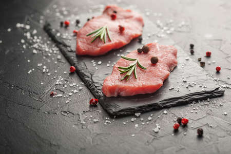 raw beef steak with rosemary and peppers on dark stoneの写真素材