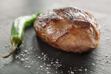 grilled steak with rosemary and chili pepper on dark stoneの写真素材