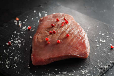 raw beef steak with rosemary and peppers on dark stoneの写真素材