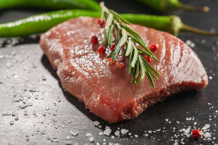 raw beef steak with rosemary and peppers on dark stoneの写真素材