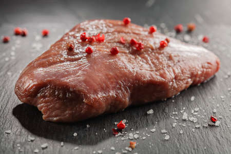 raw beef steak with rosemary and peppers on dark stoneの写真素材