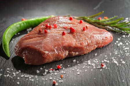raw beef steak with rosemary and peppers on dark stoneの写真素材