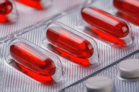 Red vitamin pills in plastic bag with other pillsの写真素材
