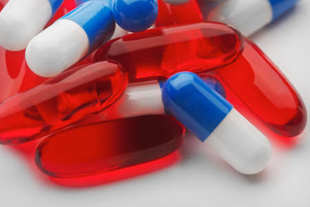 pile of red medical pill and blue penicillin capsulesの写真素材