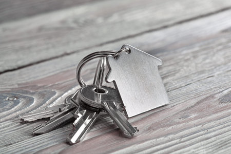 Keys to house with keychain on white wooden backgroundの写真素材
