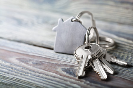 Keys to house with keychain on white wooden backgroundの写真素材