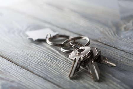 Keys to house with keychain on white wooden backgroundの写真素材