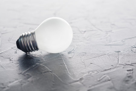 White light bulb glowing on concrete background, idea conceptの写真素材