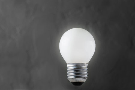 White light bulb glowing on concrete background, idea conceptの写真素材