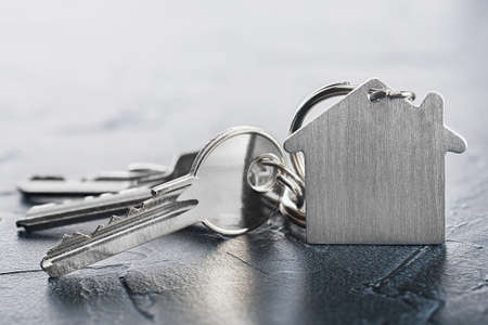 estate concept with key, keychain with house symbol, stone backgroundの写真素材